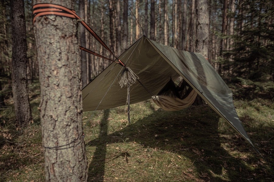 Riippumaton yläpuolelle pingotettu tarppi metsäleirissä